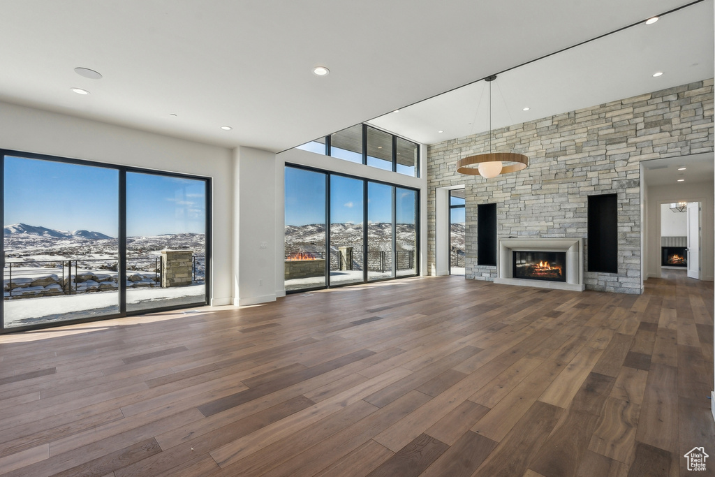 Unfurnished living room with a fireplace, a mountain view, wood finished floors, and recessed lighting