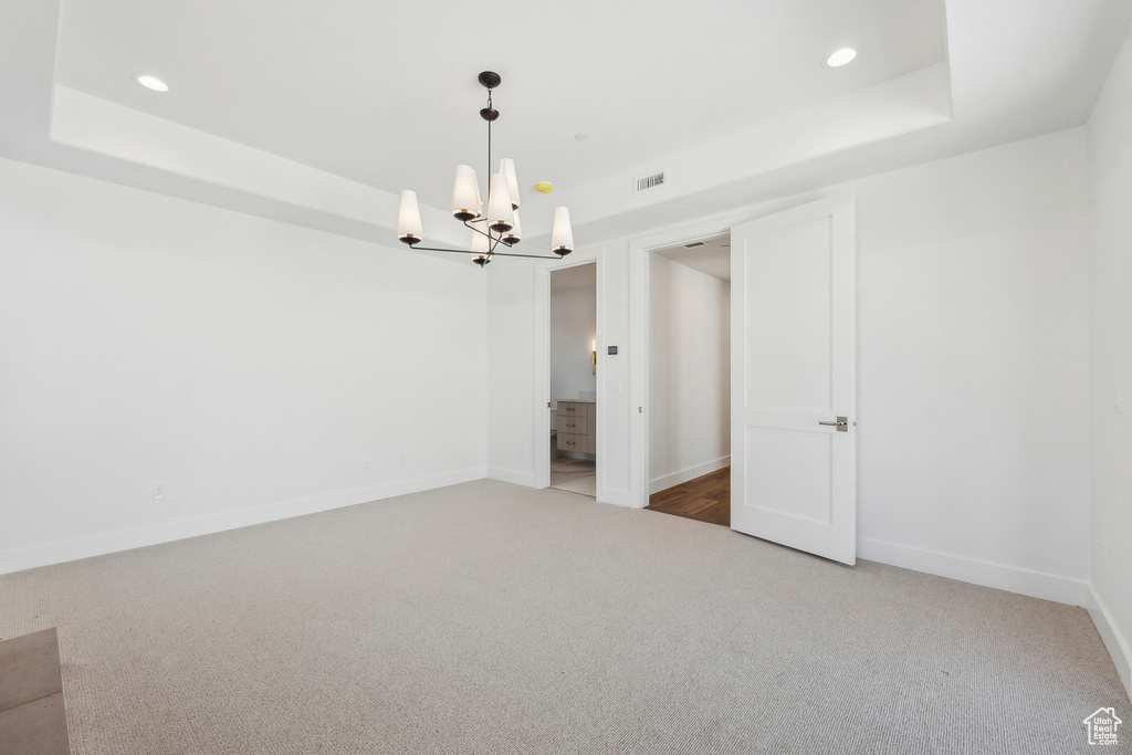 Carpeted spare room featuring a chandelier, recessed lighting, and a raised ceiling