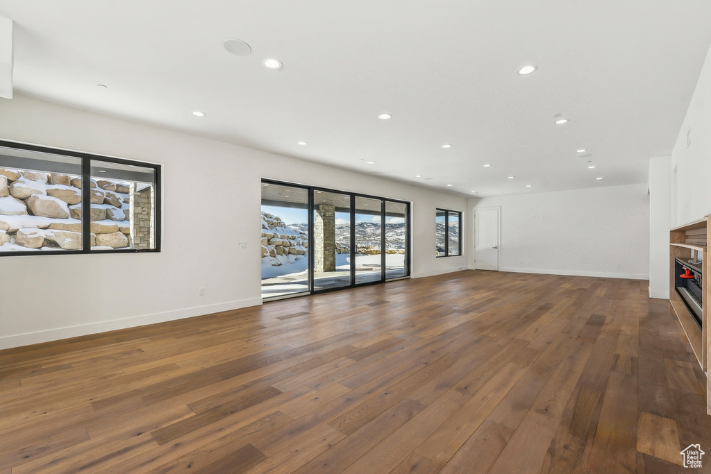 Unfurnished living room featuring wood-type flooring, recessed lighting, and a glass covered fireplace