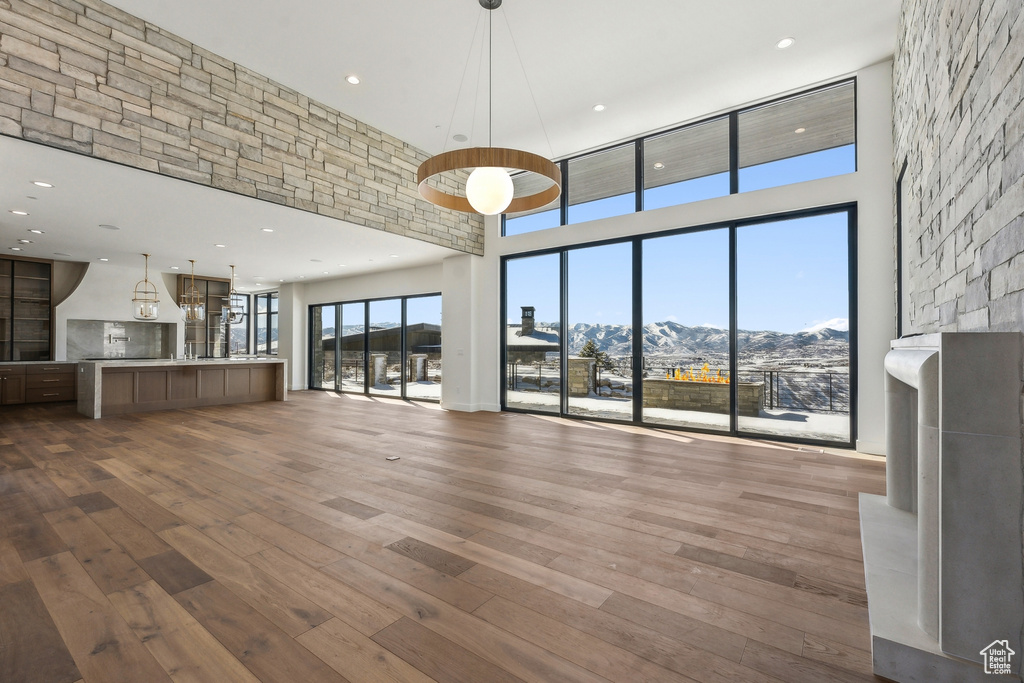 Unfurnished living room with a mountain view, a towering ceiling, hardwood / wood-style flooring, and recessed lighting