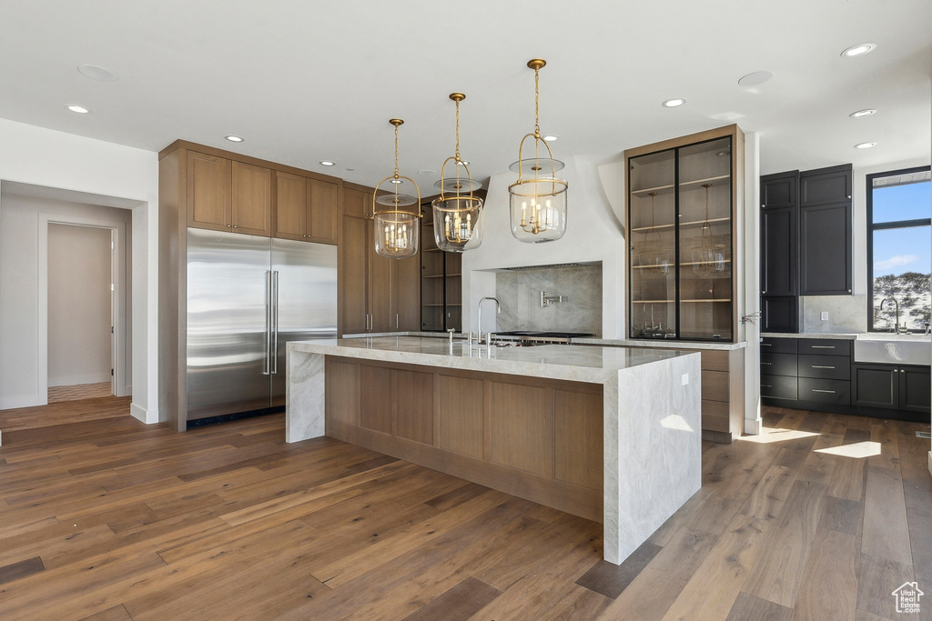 Kitchen with stainless steel built in refrigerator, backsplash, dark wood-type flooring, recessed lighting, and a spacious island