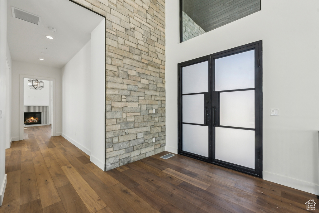 Entrance foyer featuring dark wood finished floors, a warm lit fireplace, and recessed lighting