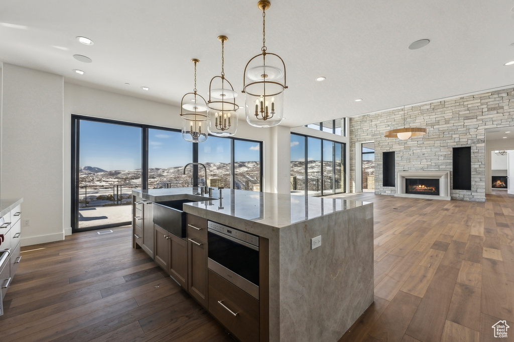 Kitchen with stainless steel microwave, dark wood-type flooring, a chandelier, a fireplace, and light stone countertops