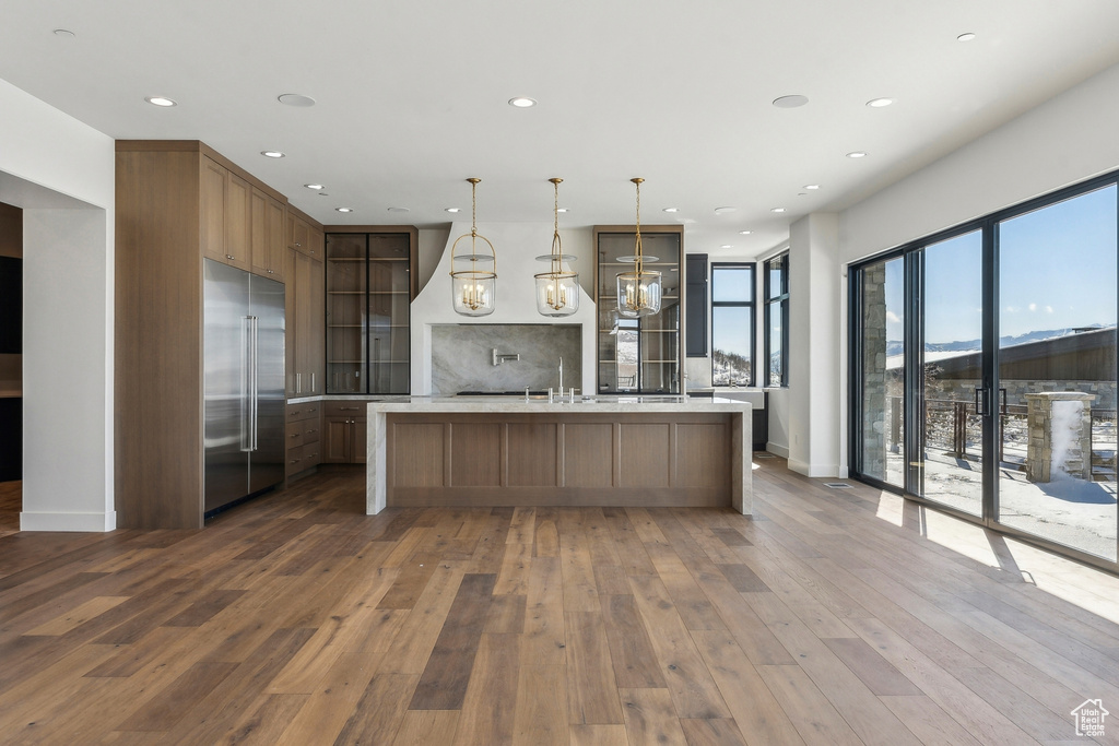 Kitchen featuring stainless steel built in fridge, dark wood-style floors, light countertops, decorative backsplash, and recessed lighting