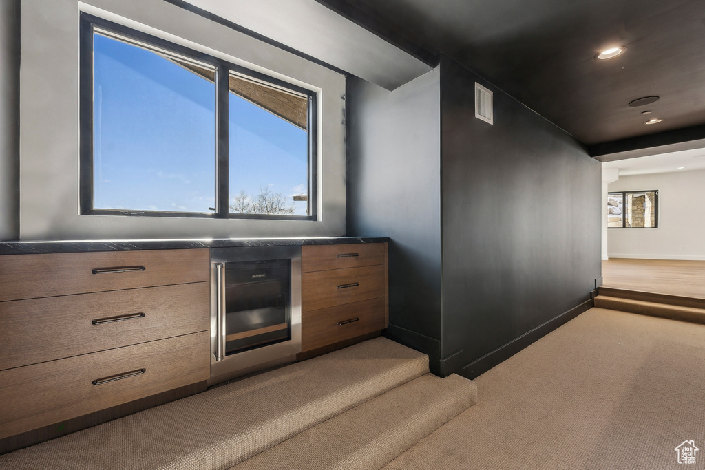 Bar area featuring light carpet, plenty of natural light, beverage cooler, and recessed lighting