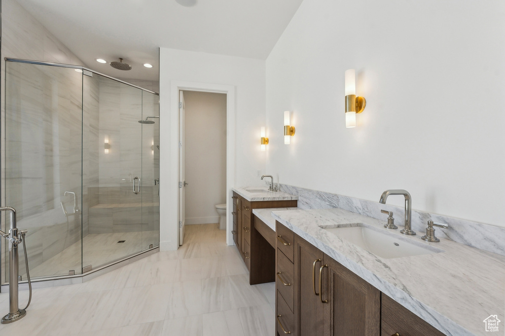 Full bathroom with a stall shower, vanity, marble look tiles, and recessed lighting