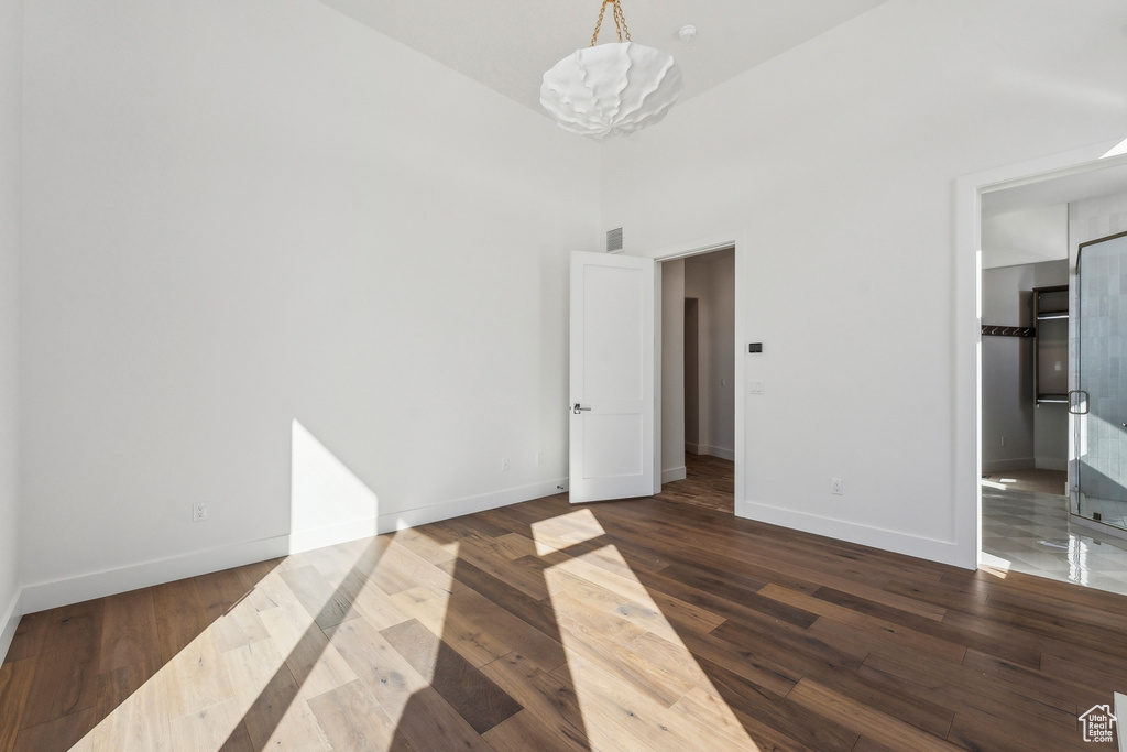 Unfurnished bedroom featuring a chandelier, dark wood finished floors, and a towering ceiling