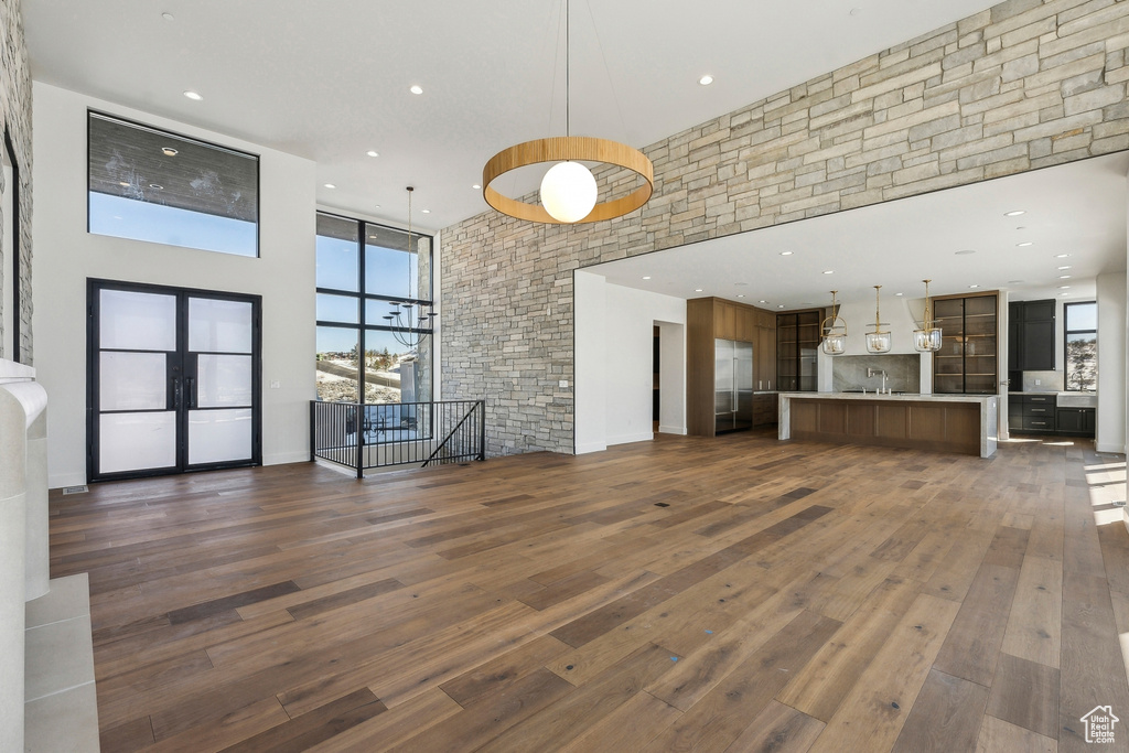 Unfurnished living room featuring a towering ceiling, dark wood-style floors, and recessed lighting
