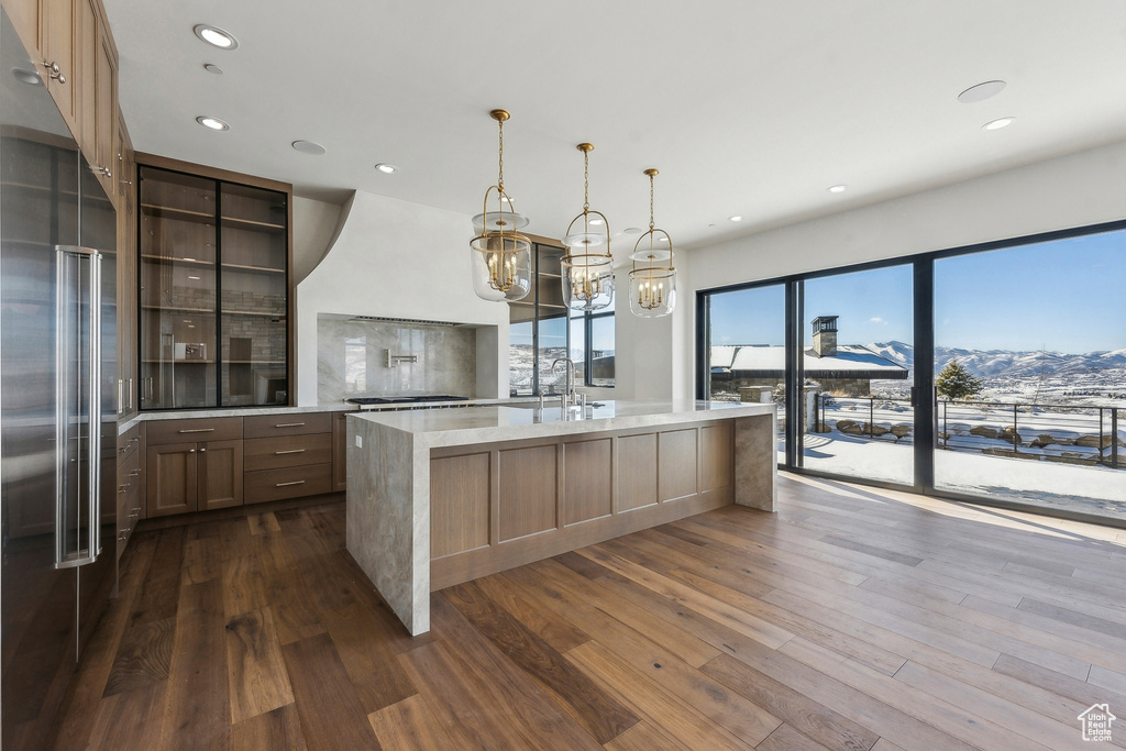 Kitchen featuring stainless steel built in refrigerator, dark wood-style flooring, a chandelier, recessed lighting, and an island with sink