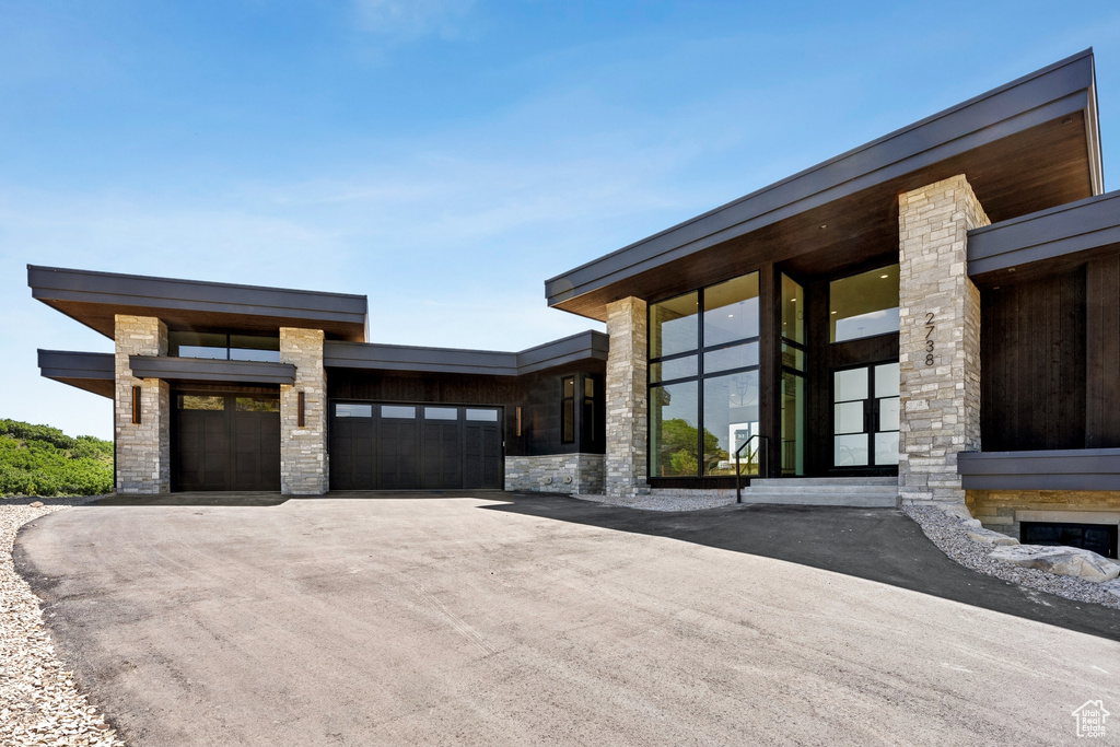 View of front of property with stone siding, an attached garage, and driveway