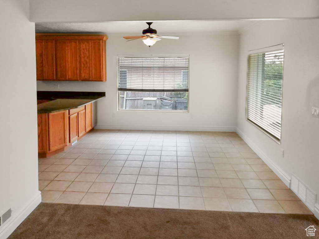 Unfurnished dining area with light tile patterned flooring and ceiling fan