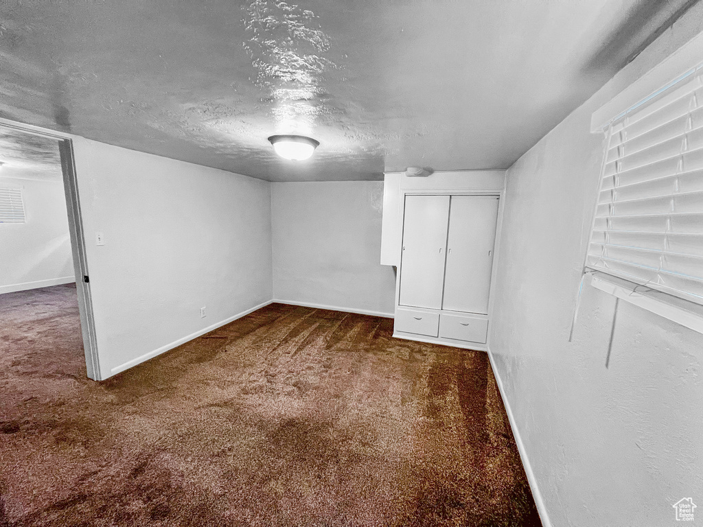 Basement featuring dark colored carpet and a textured ceiling