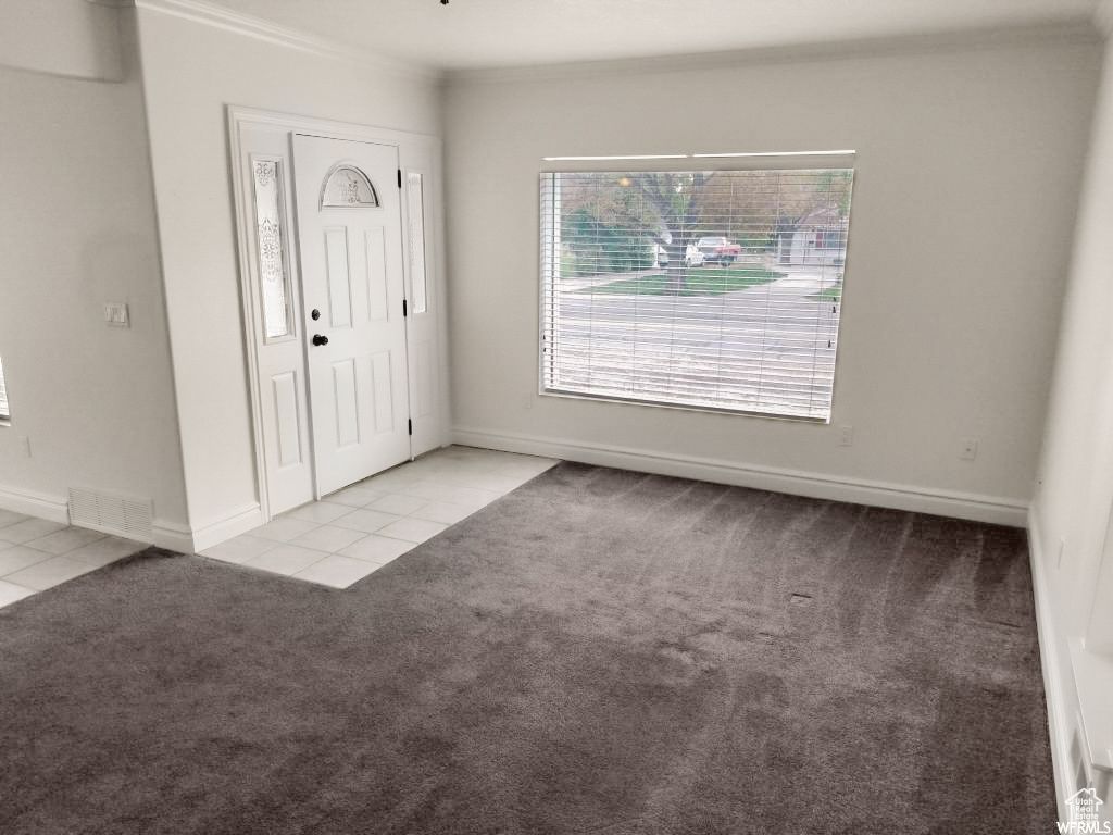 Foyer entrance featuring crown molding and light carpet