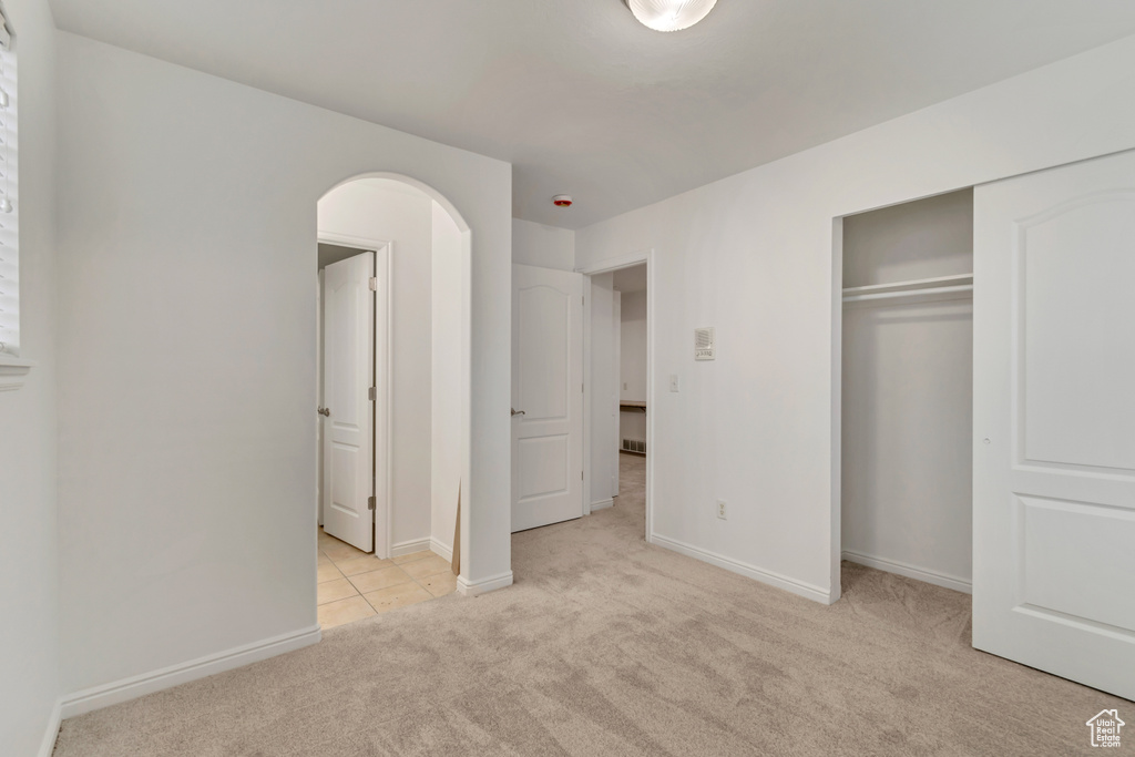 Unfurnished bedroom with light colored carpet and a closet