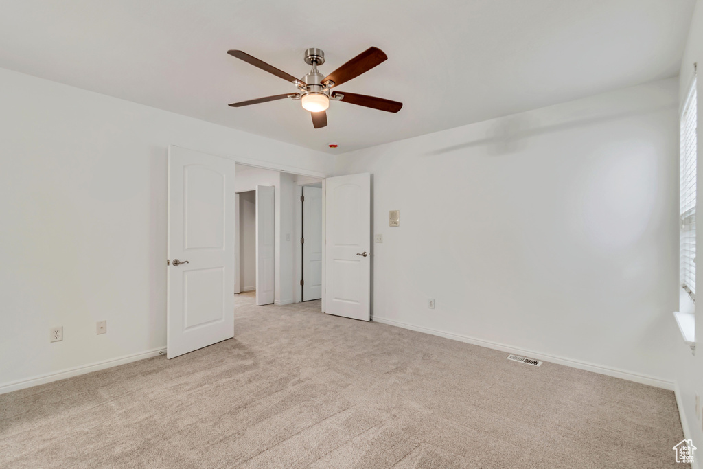 Unfurnished room with light colored carpet and ceiling fan