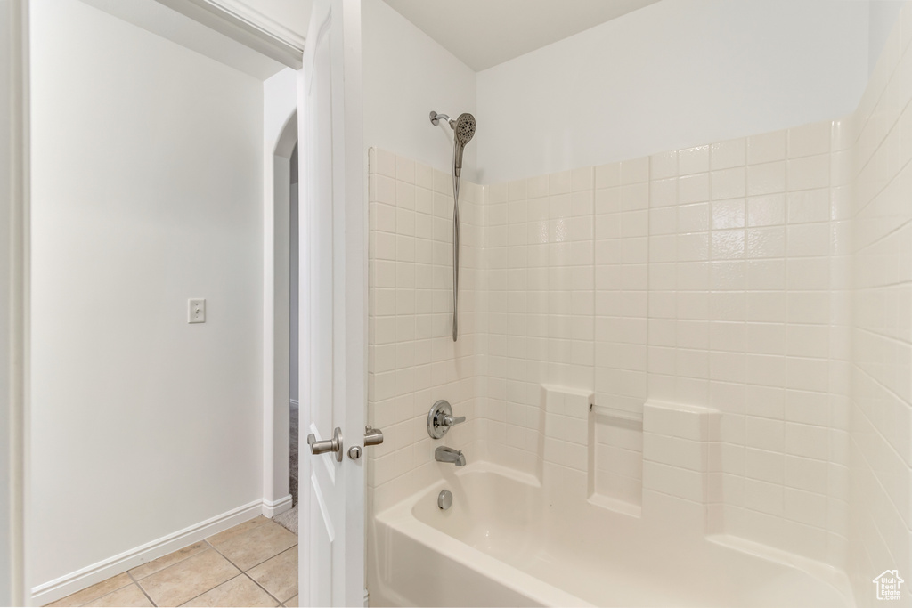 Bathroom with tile patterned floors and shower / washtub combination