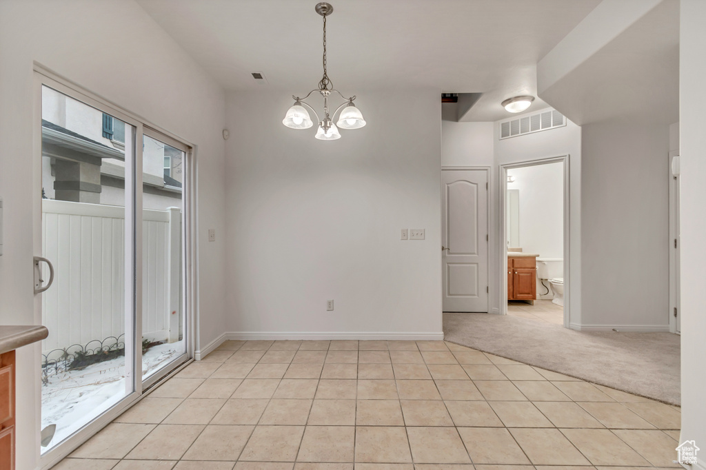 Carpeted spare room with an inviting chandelier