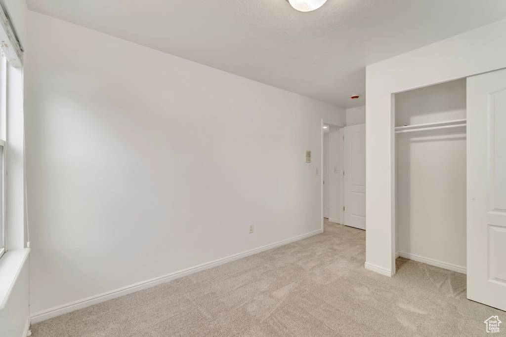 Unfurnished bedroom featuring a closet and light carpet