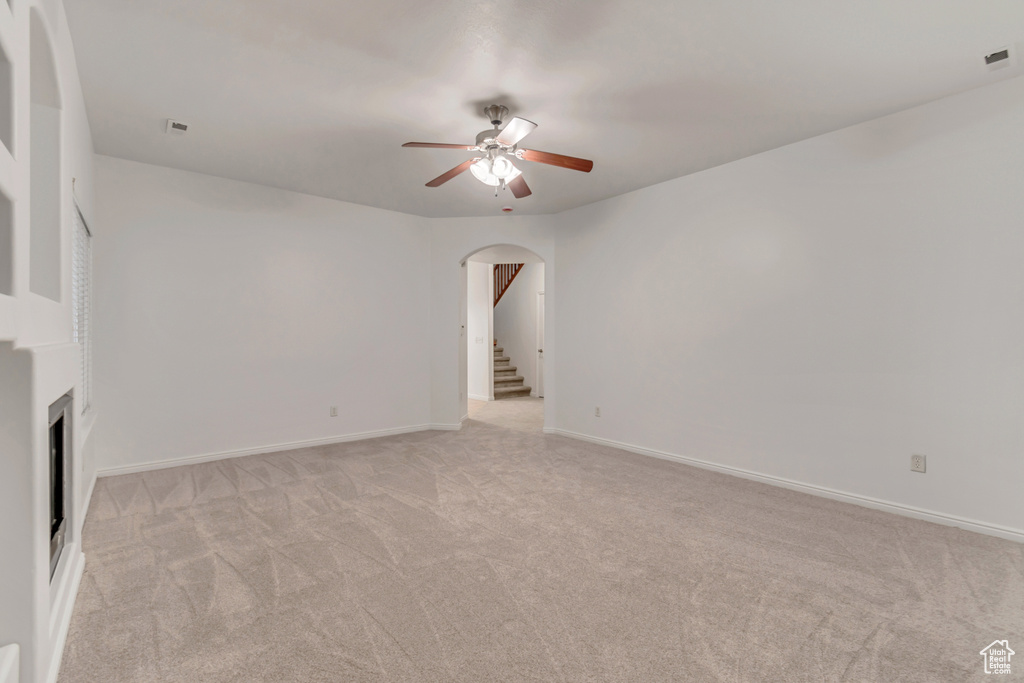 Unfurnished living room featuring light carpet and ceiling fan