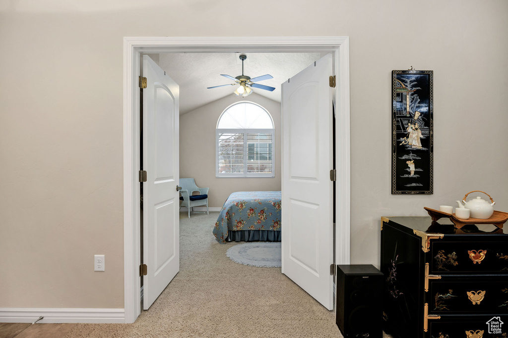 Bedroom with lofted ceiling, light colored carpet, and ceiling fan