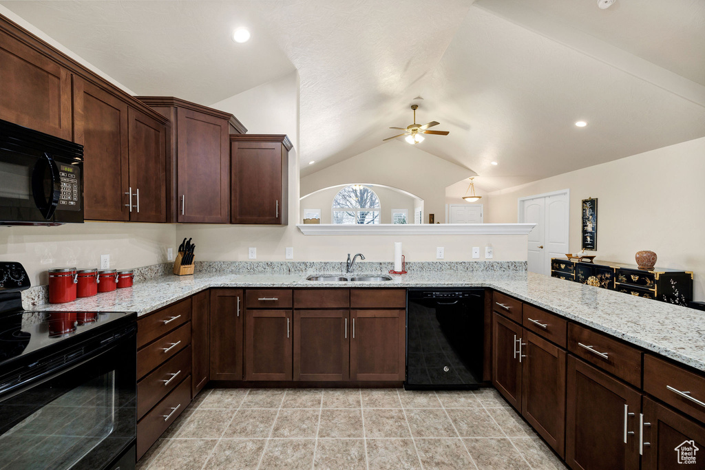 Kitchen with sink, black appliances, light stone countertops, vaulted ceiling, and kitchen peninsula