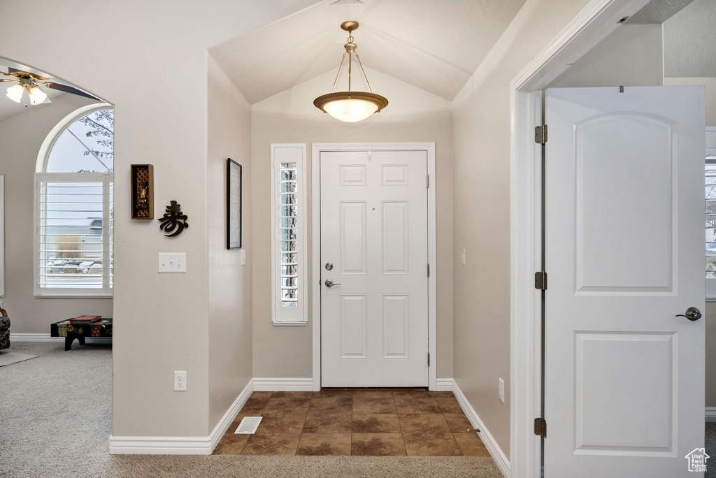 Entryway with dark tile patterned flooring, vaulted ceiling, and ceiling fan