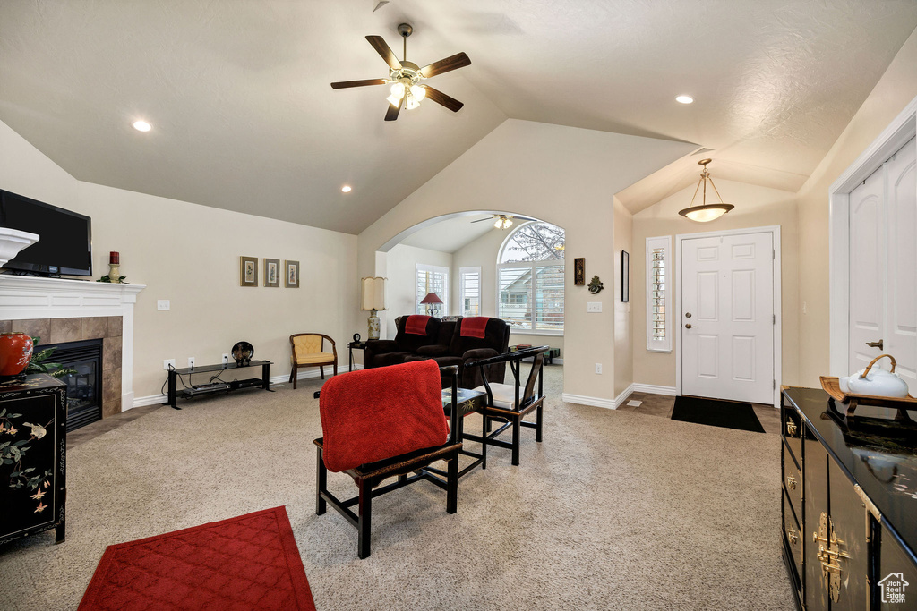 Carpeted living room with lofted ceiling, a fireplace, and ceiling fan