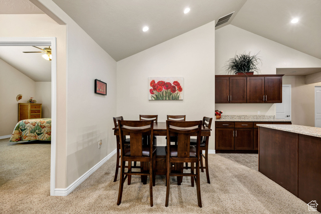 Dining room with light carpet, high vaulted ceiling, and ceiling fan