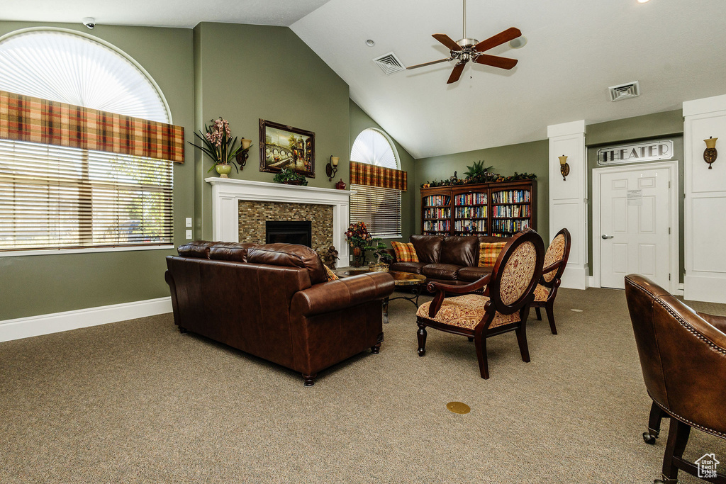 Carpeted living room with ceiling fan, high vaulted ceiling, and a fireplace