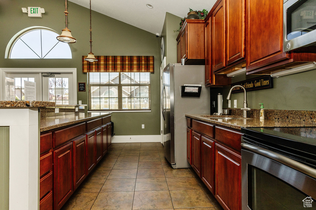 Kitchen featuring appliances with stainless steel finishes, sink, hanging light fixtures, and dark stone counters