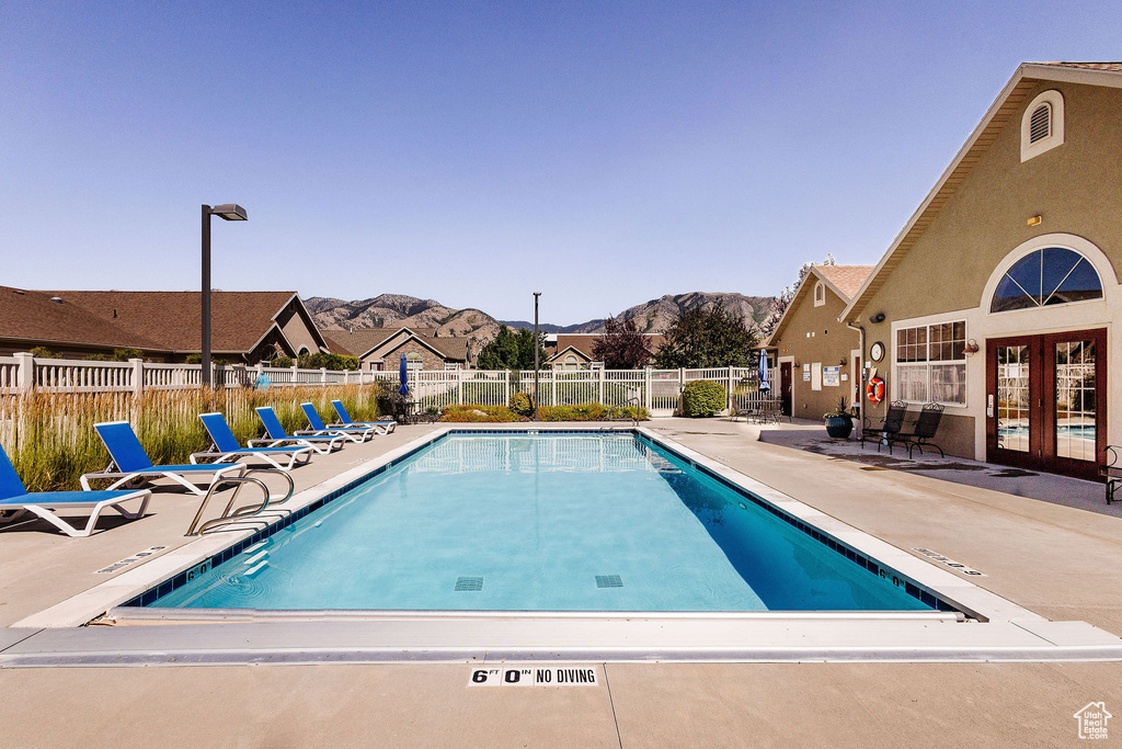 View of swimming pool with a patio, a mountain view, and french doors