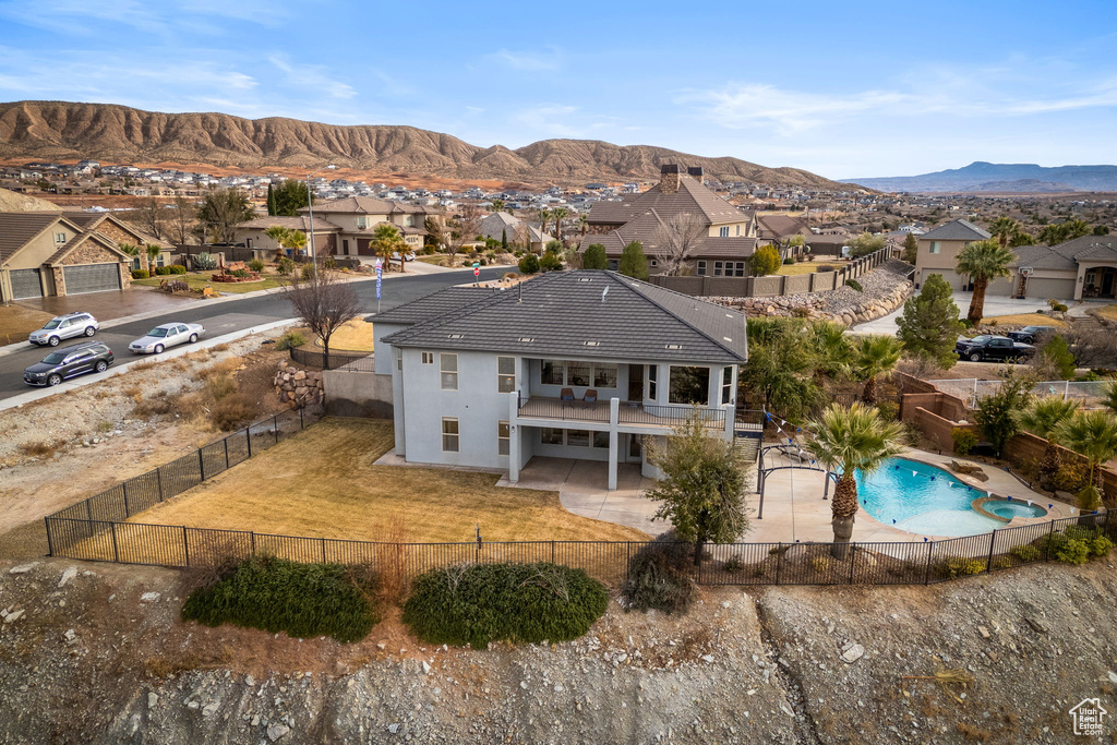 Rear view of property featuring a fenced in pool, a mountain view, a patio, and a balcony