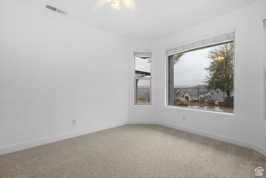 Carpeted empty room featuring ceiling fan