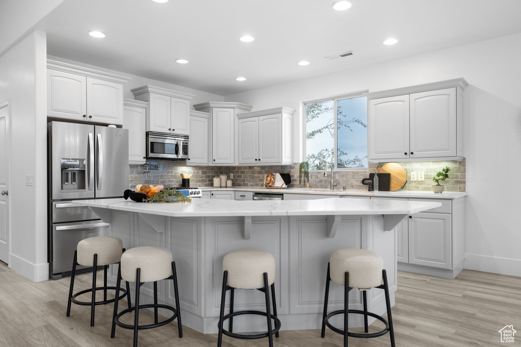 Kitchen with a breakfast bar, appliances with stainless steel finishes, a center island, and white cabinets