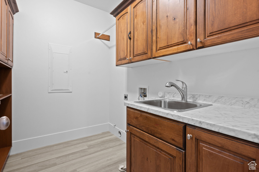 Washroom with sink, electric panel, cabinets, washer hookup, and hookup for an electric dryer