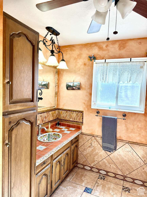 Bathroom featuring ceiling fan, vanity, and decorative backsplash