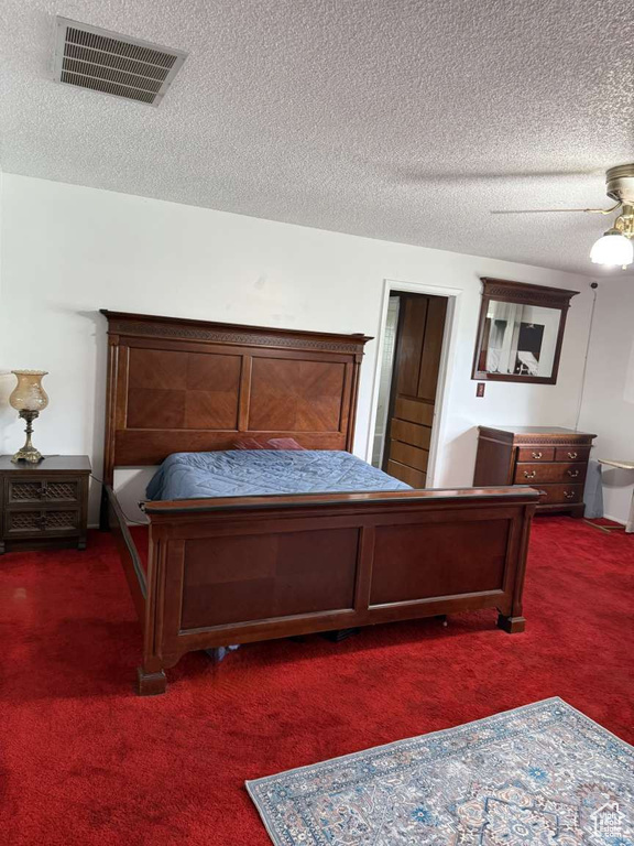 Bedroom featuring dark colored carpet, a textured ceiling, and ceiling fan