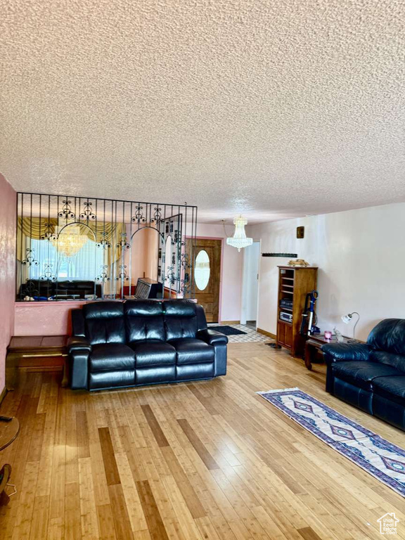 Living area with a textured ceiling, wood-type flooring, and a chandelier
