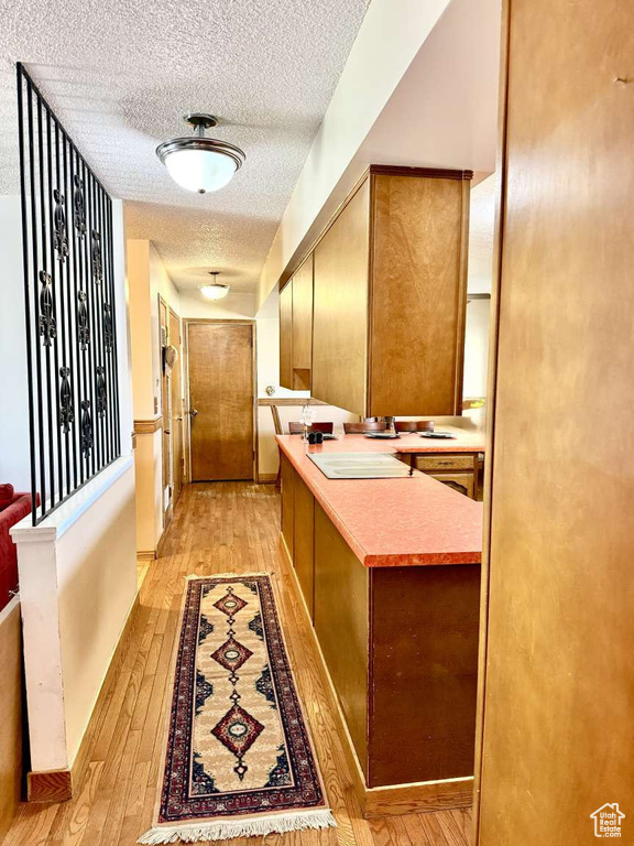 Hall with light wood-style floors and a textured ceiling