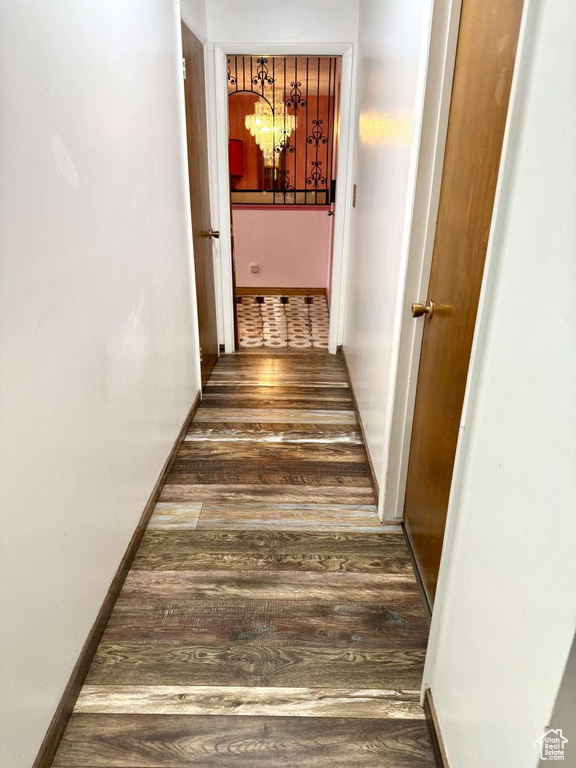 Corridor featuring a chandelier, wood finished floors, and baseboards