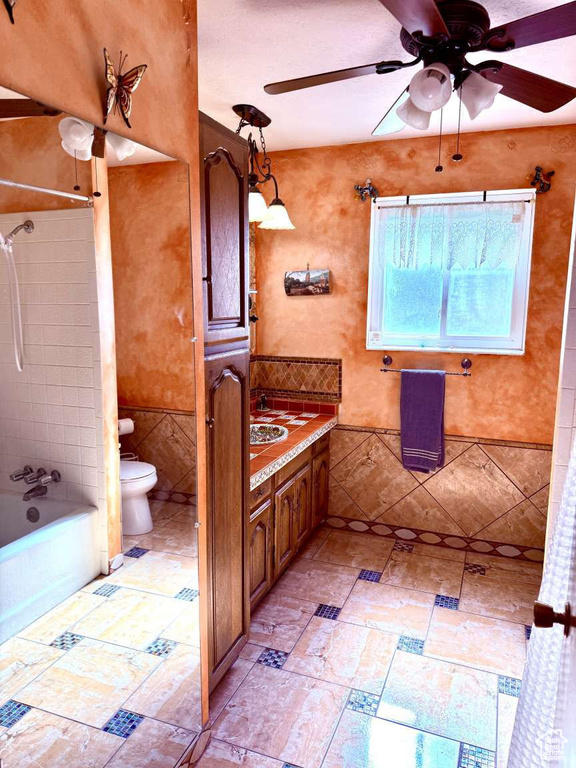 Bathroom with toilet,  shower combination, ceiling fan, and vanity