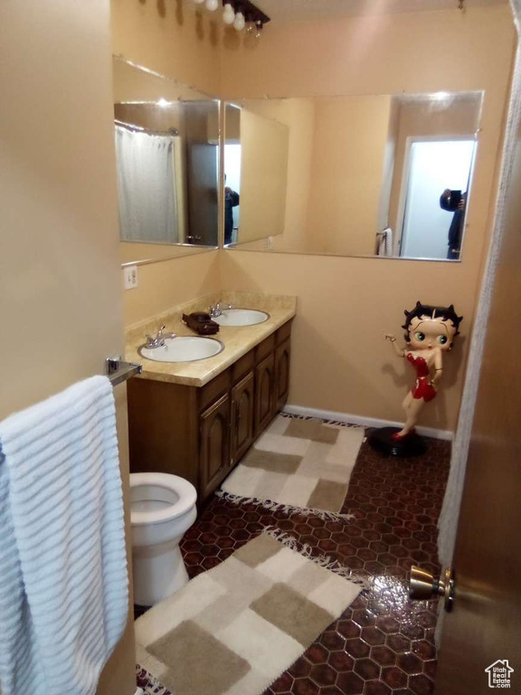 Full bathroom featuring double vanity, toilet, and tile patterned floors