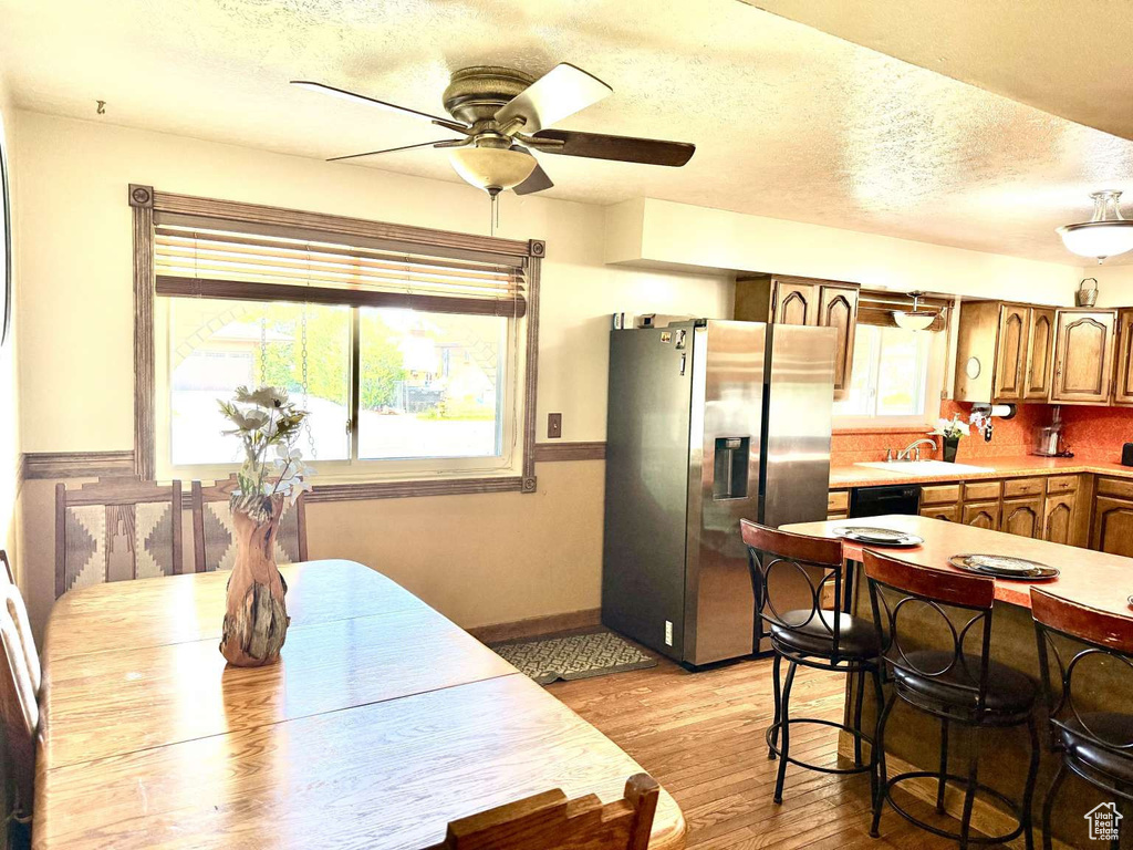 Dining area featuring ceiling fan, light wood finished floors, a textured ceiling, and baseboards