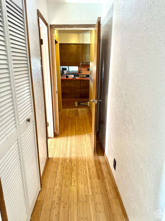 Hallway featuring a textured wall and light wood finished floors