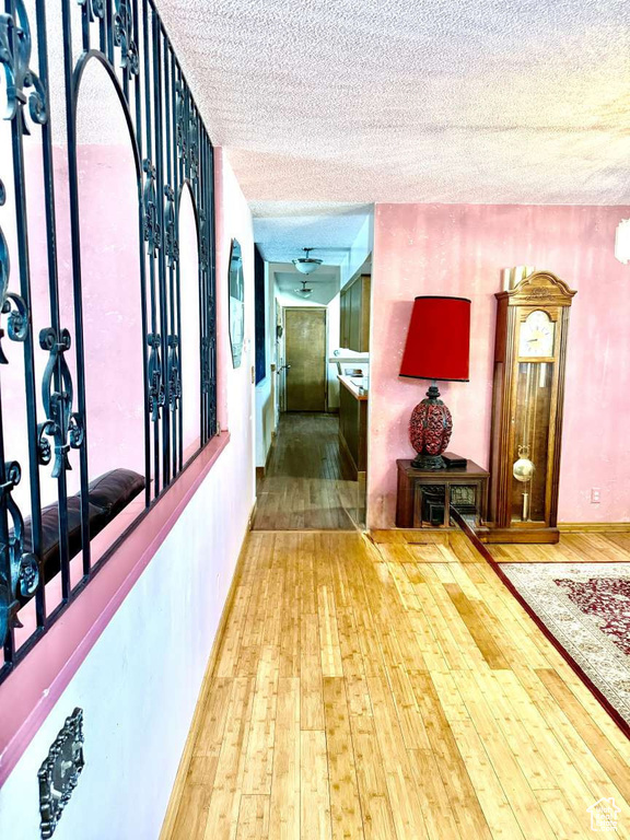 Hallway featuring hardwood / wood-style flooring, a textured ceiling, baseboards, and a wall mounted AC