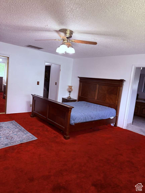 Bedroom with carpet floors, ceiling fan, a textured ceiling, and ensuite bathroom