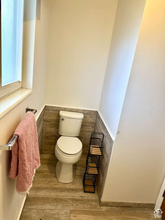 Bathroom with toilet, wood finished floors, and wainscoting
