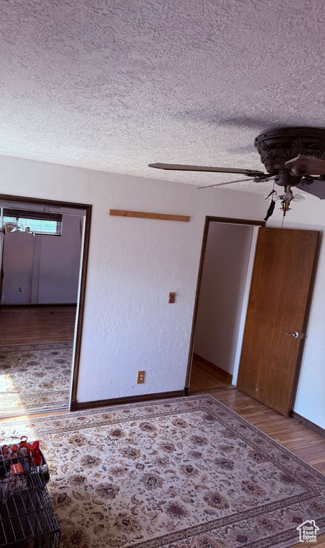 Spare room featuring a textured ceiling, wood finished floors, a ceiling fan, and baseboards