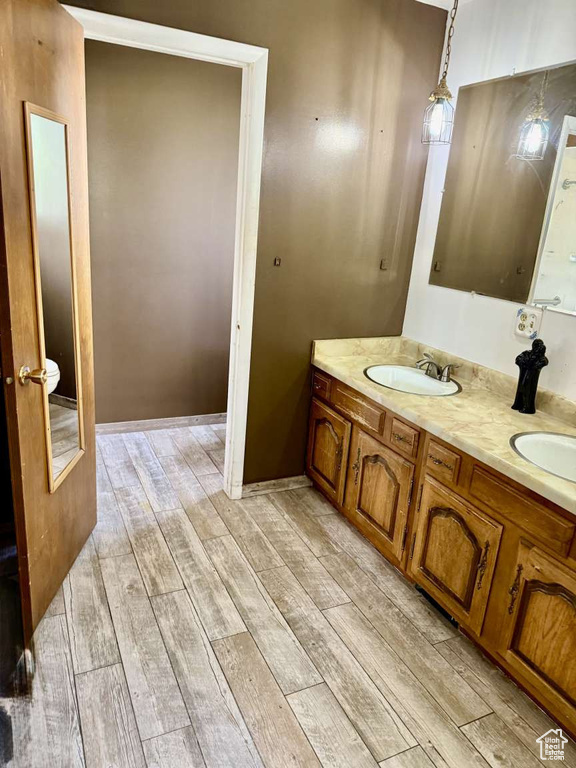Bathroom featuring wood finished floors, double vanity, and toilet