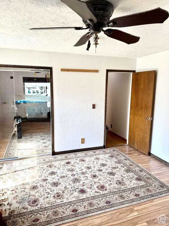 Unfurnished bedroom featuring wood finished floors, a textured ceiling, ceiling fan, and baseboards